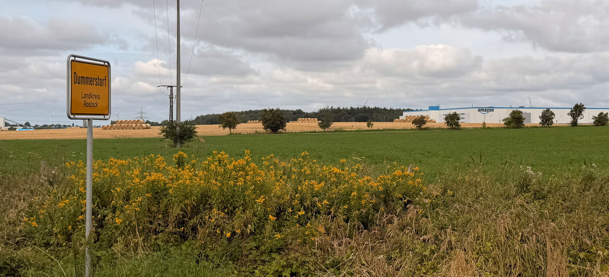 Landschaft mit Ortsschild von Dummerstorf und einem Amazon Standort im Hintergrund